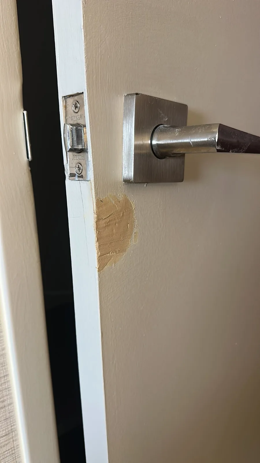 Kitchener door repair in progress with filler applied near the latch edge