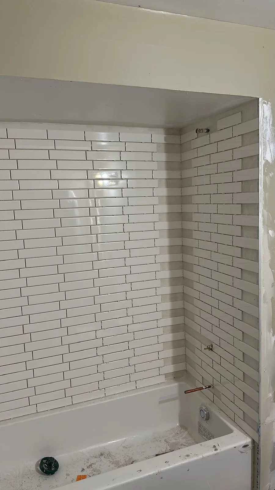 Kitchener bathtub surround with white wall tiles still being installed