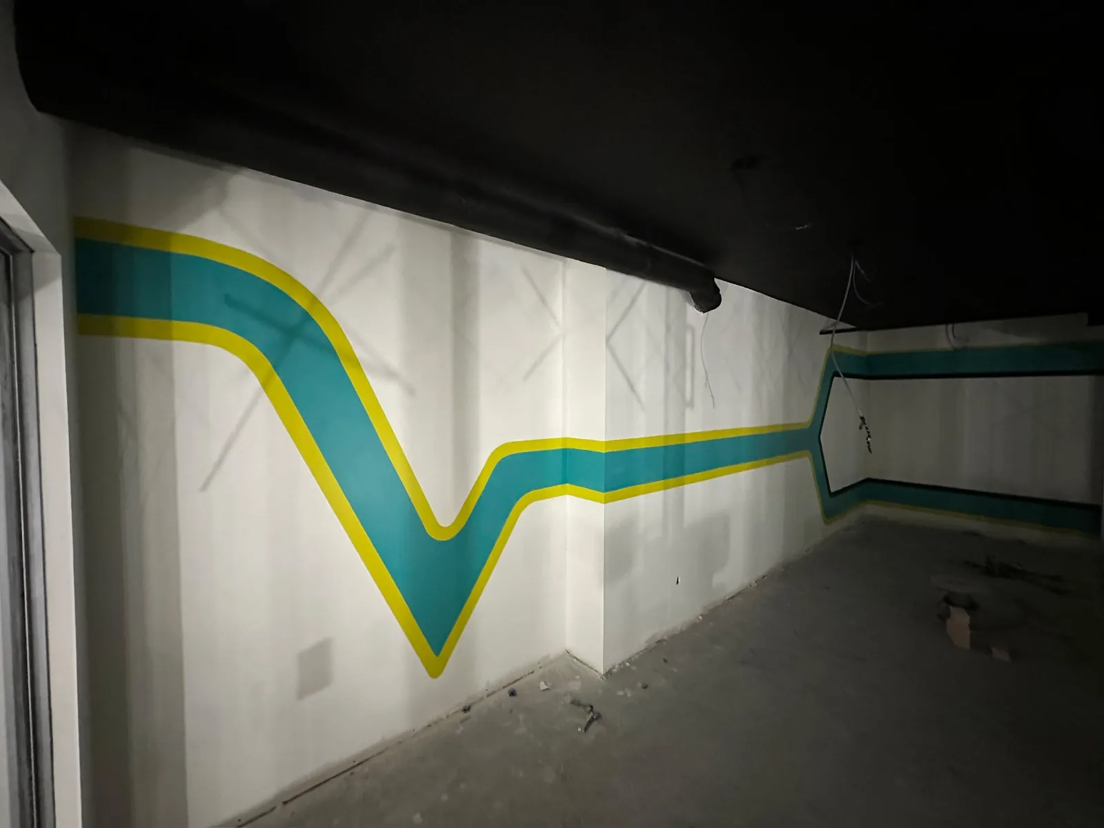 Commercial painting in Guelph featuring a teal and yellow graphic stripe on a white wall